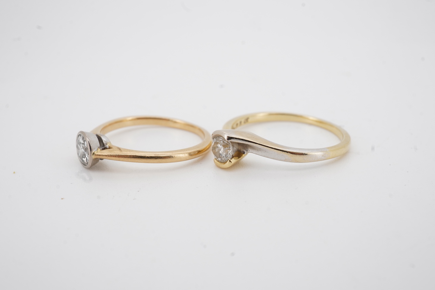 A modern two colour 18ct gold and solitaire diamond set ring, size N/O, the stone weight 0.33ct, together with a yellow metal and collet set solitaire diamond ring, size K, the stone weighing approximately 0.45ct, gross